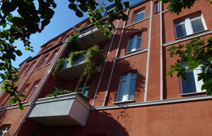 Rotes Mehrfamilienhaus mit begrünten Balkonen
